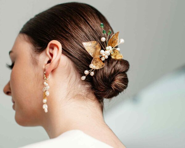 Close-up of a bridal hairstyle with delicate flower and pearl hair accessories.